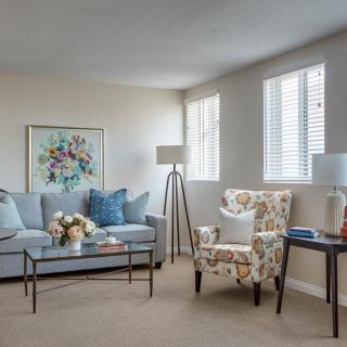 A cozy living room with a light blue sofa, floral armchair, and modern decor.