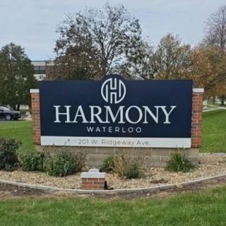 An outdoor sign for Harmony Waterloo, situated on a landscaped lawn.