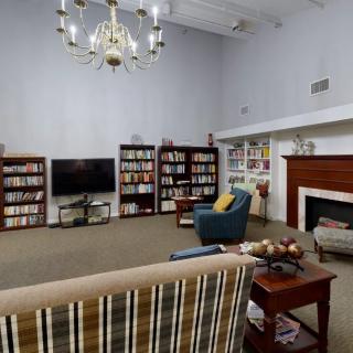 A cozy living room with bookshelves, a TV, an armchair, and a fireplace.