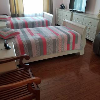 A cozy bedroom with twin beds featuring striped bedding, a dresser, and a television.