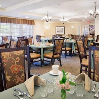 A spacious dining room with elegantly set tables and upholstered chairs.