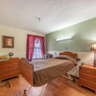 A cozy hospital bedroom featuring a bed, nightstands, and warm lighting.