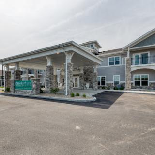 View of a modern hotel entrance with a covered portico and landscaped surroundings.