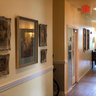 A warmly lit hallway adorned with framed artwork and subtle ambient lighting.