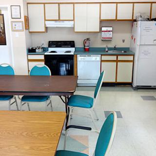 A community kitchen with tables, chairs, and common appliances.