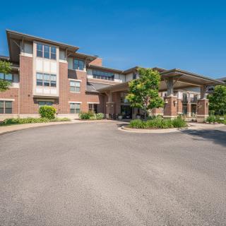 A modern residential apartment complex with a landscaped entrance and clear blue sky.