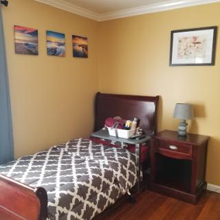 A cozy bedroom featuring a neatly made bed, a nightstand with a lamp, and decorative artwork on the walls.