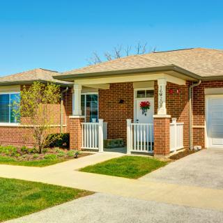 A charming brick bungalow with a tidy front yard and driveway.
