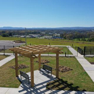 A pergola with benches in a scenic outdoor setting on a sunny day.