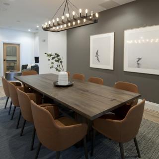 A modern dining room with a large wooden table, stylish chairs, and an elegant chandelier.