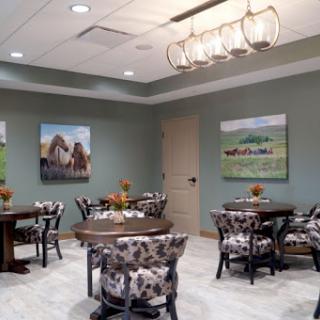 A cozy dining area featuring elegantly arranged tables, floral-patterned chairs, and artful wall decorations.