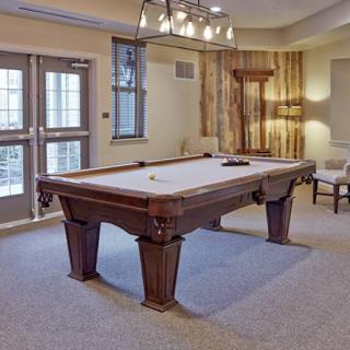 A well-lit game room featuring a classic wooden pool table.