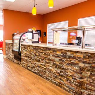 A modern cafe interior featuring a stone counter and vibrant orange walls.