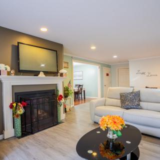 A modern living room featuring a cozy fireplace, a large sofa, and a sleek coffee table adorned with flowers.