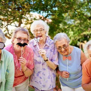 A group of seniors having fun with playful props outdoors.