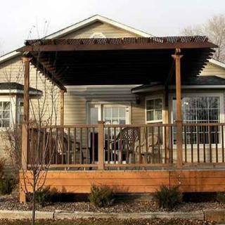 A cozy house with a wooden deck and pergola, featuring outdoor seating.
