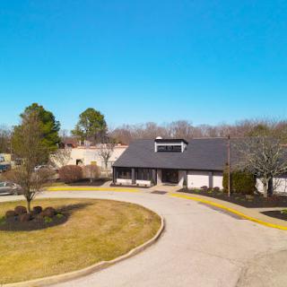 A photo capturing a modern building surrounded by a well-maintained landscape and clear blue skies.