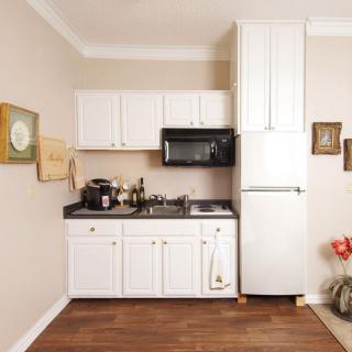 A compact kitchen setup with white cabinets, a microwave, refrigerator, and a coffee maker on the countertop.