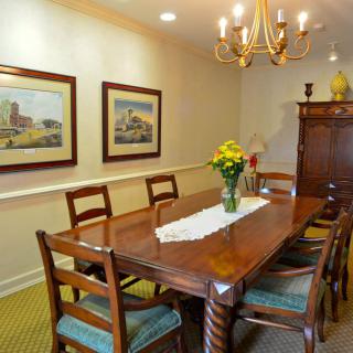A cozy dining room featuring a wooden table with chairs, a chandelier, and artwork on the walls.