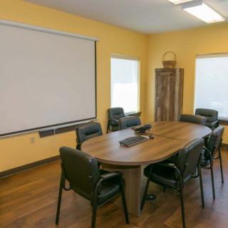 A well-organized conference room equipped with a large table, chairs, and a projector screen.