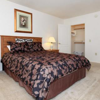 A cozy bedroom with a floral bedspread, lamp, and open closet.