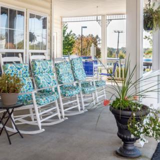 A cozy porch featuring patterned rocking chairs and potted plants, offering a relaxing outdoor seating area.
