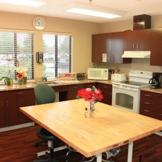A modern kitchen featuring a large wood table, various appliances, and natural light from the windows.