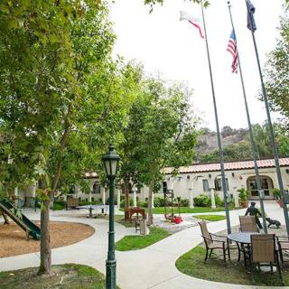 A peaceful courtyard with flags, trees, and seating areas.