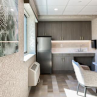A modern kitchenette featuring sleek cabinets, a refrigerator, and comfortable seating.