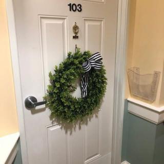 A door with the number 103 is decorated with a green wreath and black-and-white striped bow.