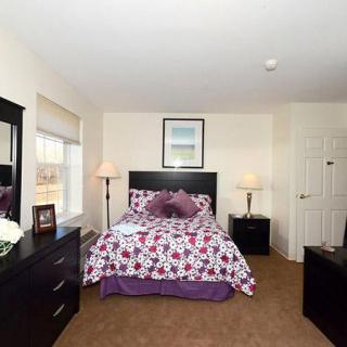 A cozy bedroom with a floral bedspread, two lamps, and a dresser with a mirror.