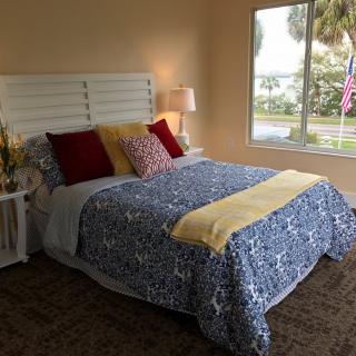 A cozy bedroom with patterned bedding and colorful cushions next to a large window.