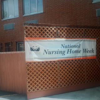 A banner promoting National Nursing Home Week displayed outside a building.