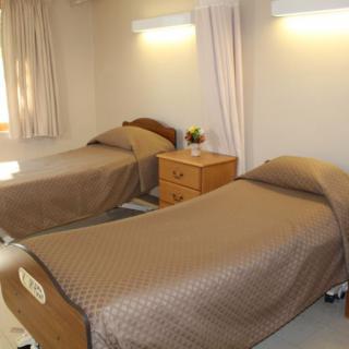 A hospital room with two single beds and a small bedside table.