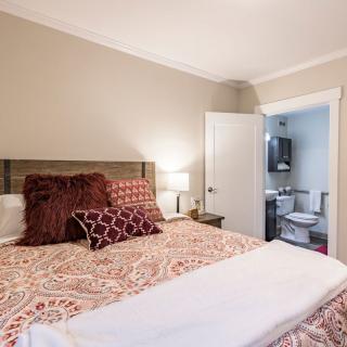 A cozy bedroom with decorative pillows and an adjacent bathroom.