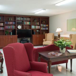 A cozy living room with red armchairs, a bookshelf, and a television.