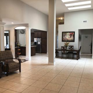 A spacious and modern living room with an open dining area, featuring tiled floors and ample natural light.