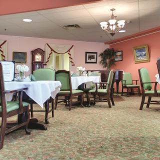 A cozy dining area with neatly arranged tables and chairs, adorned with elegant decor and a chandelier.