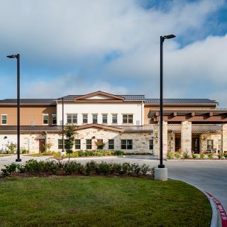 A modern building with a well-maintained landscape and clear blue sky.