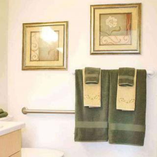 A neatly arranged bathroom with green towels and framed wall art.