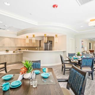 A modern dining area with an open kitchen, featuring stylish furniture and decor.