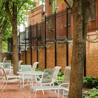 A serene outdoor seating area surrounded by trees and a brick wall.