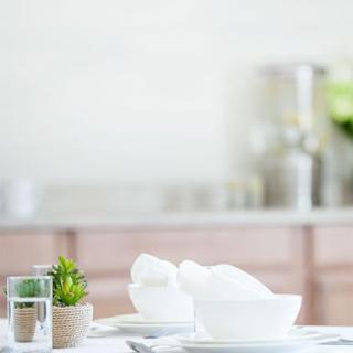 A beautifully arranged dining table featuring minimalist white dinnerware and a touch of greenery.