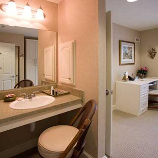 A cozy bathroom with a vanity mirror, sink, and cushioned chair.