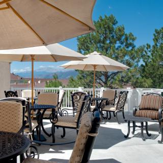 A sunny outdoor patio with tables, chairs, and umbrellas, offering a relaxing atmosphere.