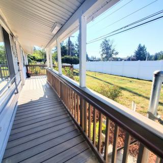 A sunny porch overlooking a grassy landscape with white fencing.