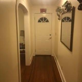 A cozy hallway with a mirror and decorative elements leading to a white door.