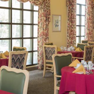 A cozy dining room with elegantly set tables and large windows.