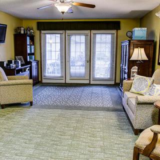 A cozy living room with comfortable sofas and a TV, featuring large glass doors leading outside.