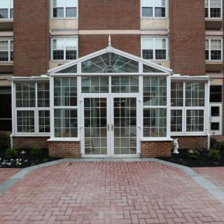 The image shows the glass entrance of a brick building with multiple windows.